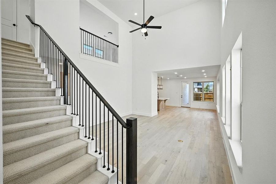 Stairway featuring wood finished floors, a high ceiling, recessed lighting, and a ceiling fan Stairway featuring wood finished floors, a high ceiling, recessed lighting, and a ceiling fan