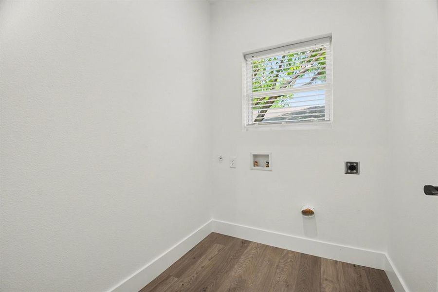 Dedicated laundry area featuring a window with blinds, white walls, and wood-look flooring