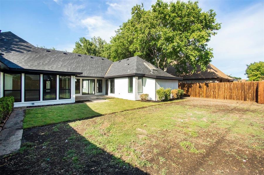 Rear view of property with a yard and a sunroom