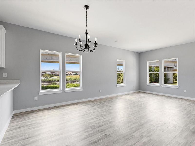 Unfurnished dining area with a chandelier, baseboards, and light wood-type flooring