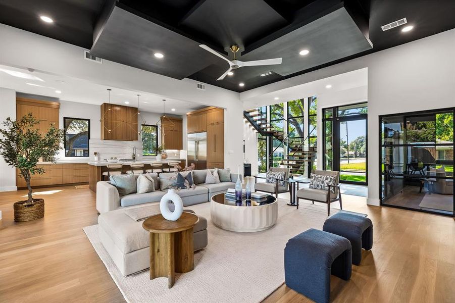 Living room with stairway, plenty of natural light, light wood finished floors, recessed lighting, and a ceiling fan Living room with stairway, plenty of natural light, light wood finished floors, recessed lighting, and a ceiling fan