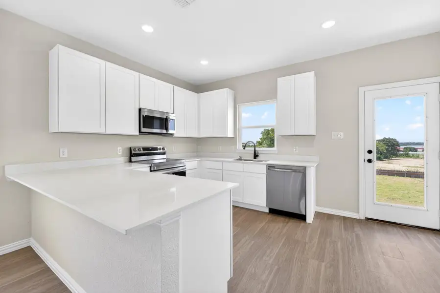 Streamlined cabinetry and pristine countertops define this contemporary cooking space with backyard access.