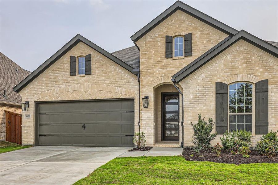 French provincial home with brick siding and concrete driveway French provincial home with brick siding and concrete driveway