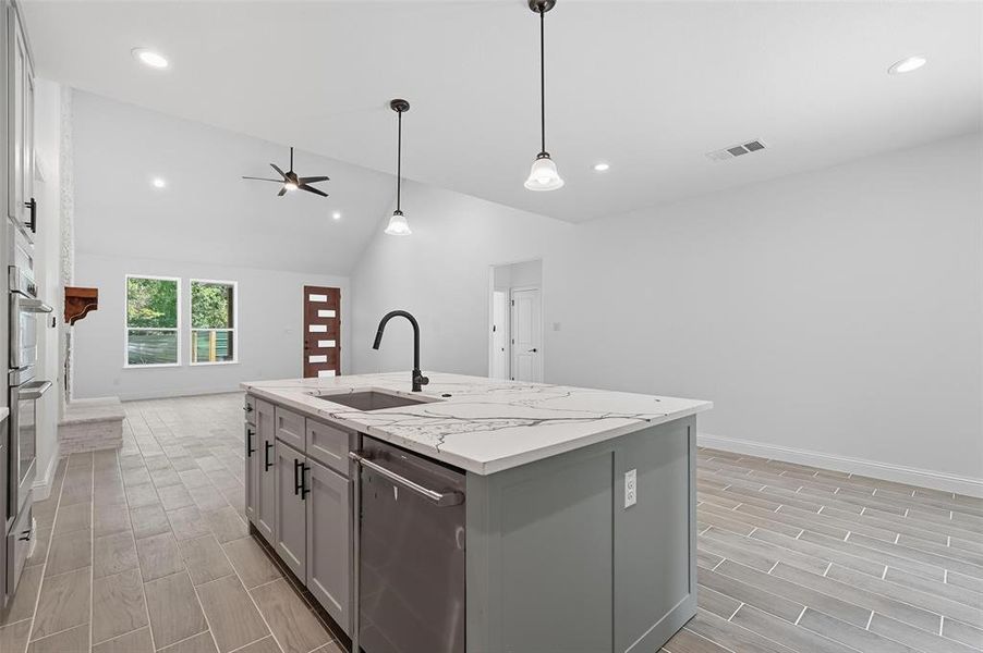 Kitchen featuring wood tiled floors, a center island with sink, appliances with stainless steel finishes, gray cabinetry, and decorative light fixtures Kitchen featuring wood tiled floors, a center island with sink, appliances with stainless steel finishes, gray cabinetry, and decorative light fixtures