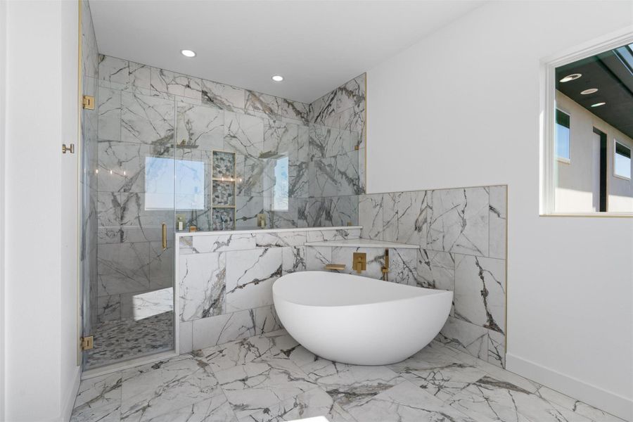 Bathroom featuring a freestanding bath, a marble finish shower, light marble finish flooring, healthy amount of natural light, and recessed lighting