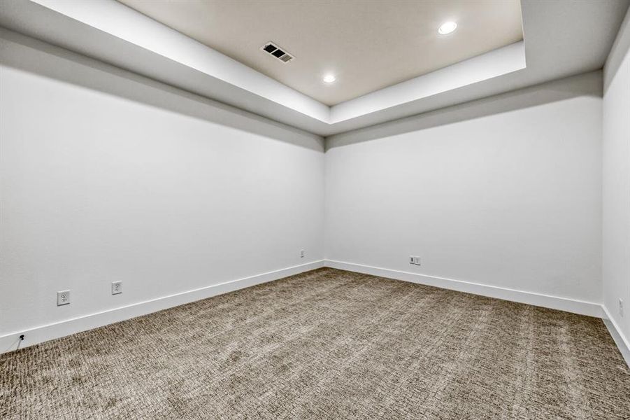 Empty room featuring recessed lighting, light colored carpet, and a raised ceiling