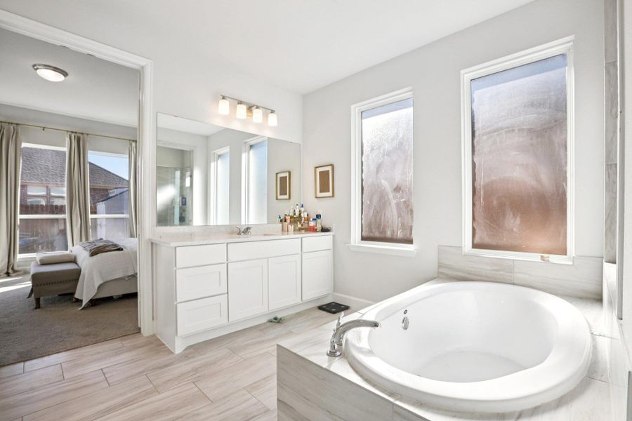 Ensuite bathroom featuring vanity and a bath