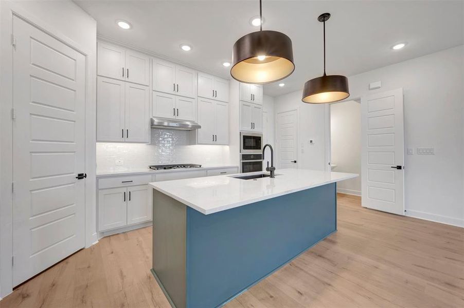 Contemporary kitchen featuring a blue-toned island with a white countertop and dark pendant lighting Contemporary kitchen featuring a blue-toned island with a white countertop and dark pendant lighting