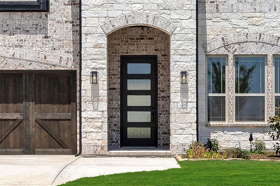 Home entrance with black glass-panel front door set in arched stone surround with wall sconces