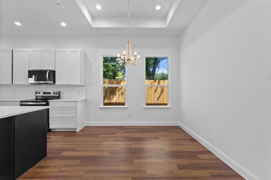 Kitchen featuring dark wood finished floors, a chandelier, light countertops, recessed lighting, and a raised ceiling Kitchen featuring dark wood finished floors, a chandelier, light countertops, recessed lighting, and a raised ceiling