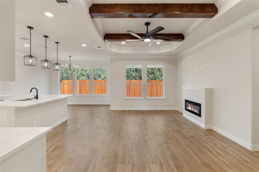 Unfurnished living room featuring ceiling fan with notable chandelier, light wood-type flooring, ornamental molding, and sink