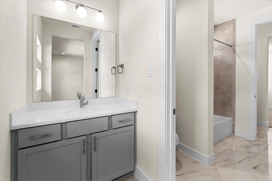 Bathroom 4 with modern quartz vanity, spacious layout, and tub-shower combo with tile surround.