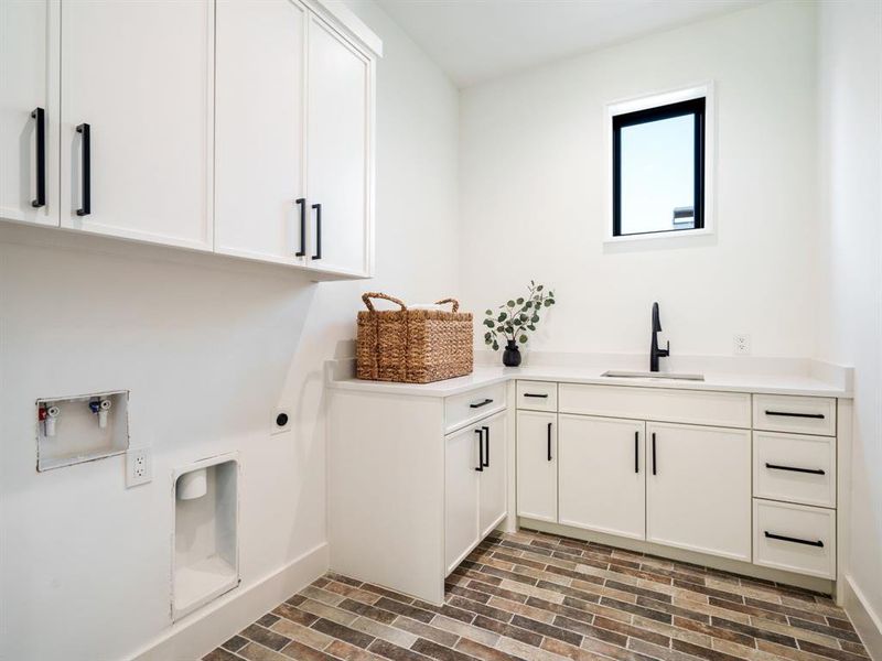 Laundry area featuring brick floors, cabinet space, electric dryer hookup, and washer hookup