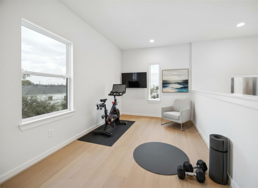 Third-floor study features bright windows with plenty of natural light and a view from the railing down into the living room, adding connection and openness to the space. *Virtually staged*
