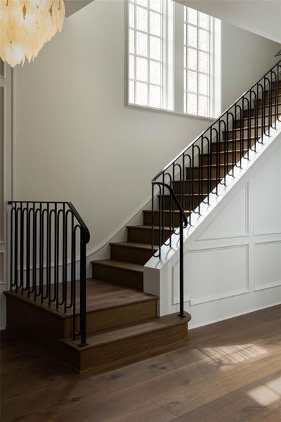 Designer stair case boasts custom steel rail design, glowing natural light through the aluminum clad windows, as well as a beautiful light fixture and detailed wall paneling. Designer stair case boasts custom steel rail design, glowing natural light through the aluminum clad windows, as well as a beautiful light fixture and detailed wall paneling.