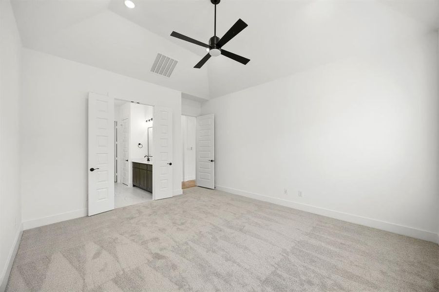 Unfurnished bedroom with light colored carpet, a ceiling fan, connected bathroom, lofted ceiling, and recessed lighting