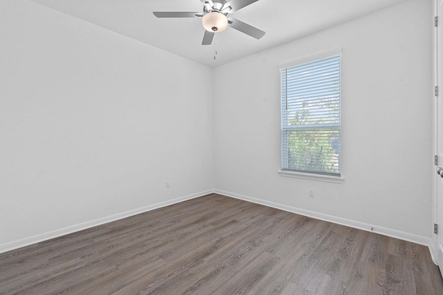 Unfurnished room with plenty of natural light, wood finished floors, baseboards, and ceiling fan