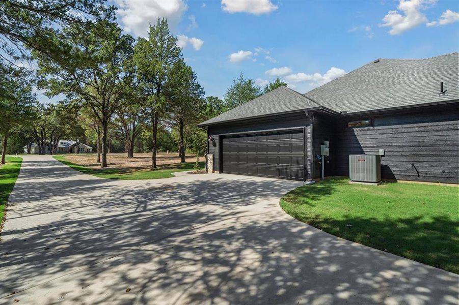 View of property exterior featuring roof with shingles, a yard, driveway, and an attached garage