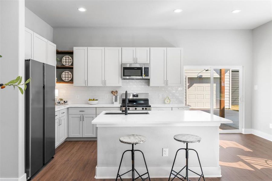 Kitchen featuring backsplash, stainless steel appliances, open shelves, dark wood finished floors, and white cabinets