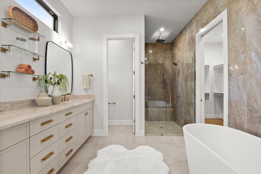 Bathroom featuring a shower stall, vanity, a freestanding bath, and a spacious closet