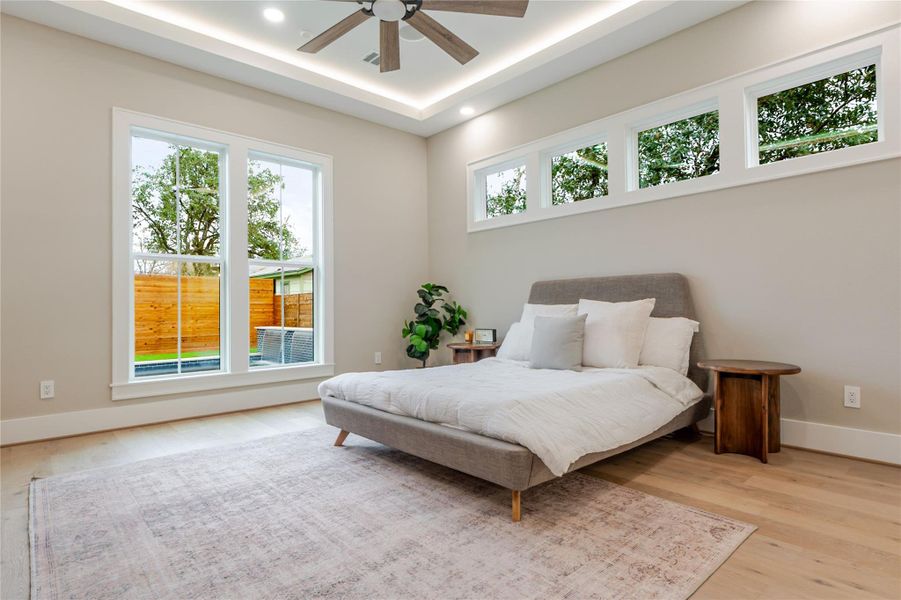 Bedroom with ceiling fan, light wood-type flooring, a tray ceiling, and recessed lighting