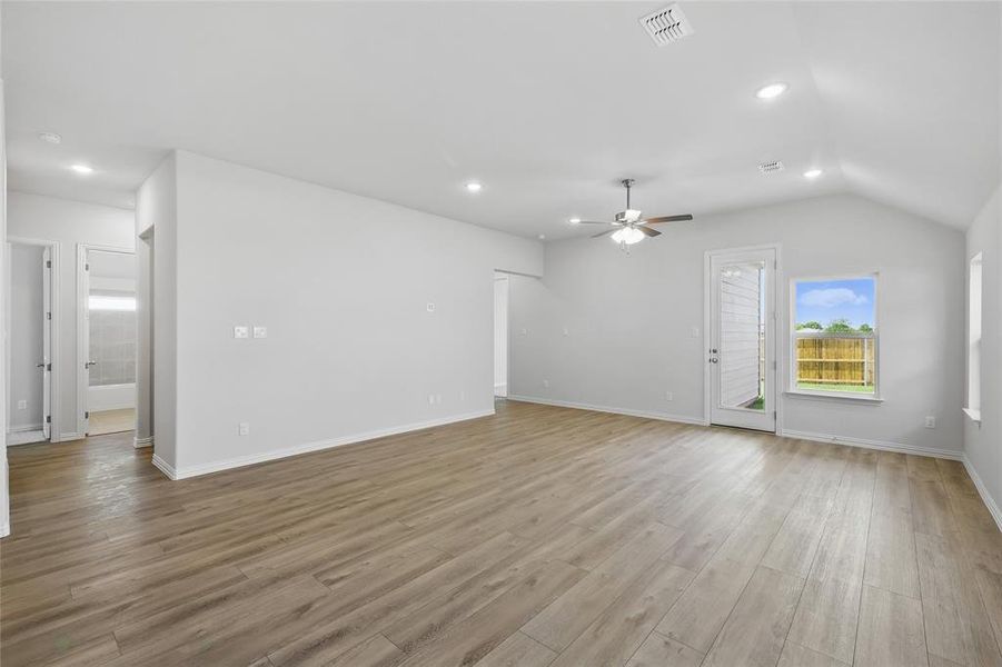 Unfurnished living room with a ceiling fan, light wood-style flooring, recessed lighting, lofted ceiling, and baseboards Unfurnished living room with a ceiling fan, light wood-style flooring, recessed lighting, lofted ceiling, and baseboards