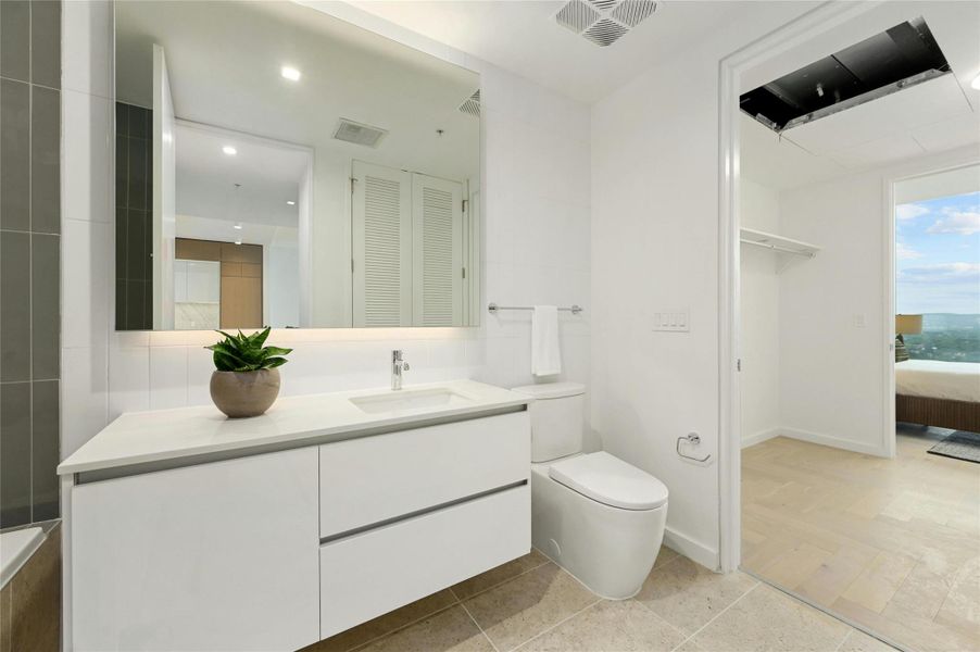 Full secondary bathroom featuring a sleek floating vanity, integrated storage, and modern fixtures, conveniently connected to the adjacent bedroom and walk-in closet.