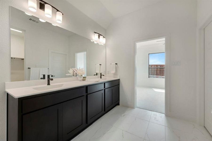 Bathroom featuring double vanity, light marble finish flooring, and lofted ceiling Bathroom featuring double vanity, light marble finish flooring, and lofted ceiling