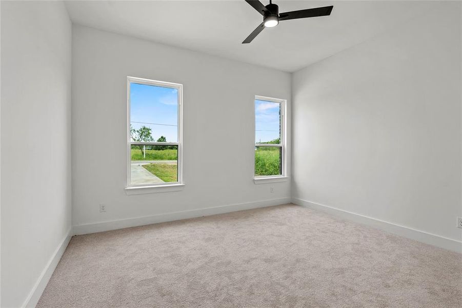 Carpeted empty room with a ceiling fan and baseboards
