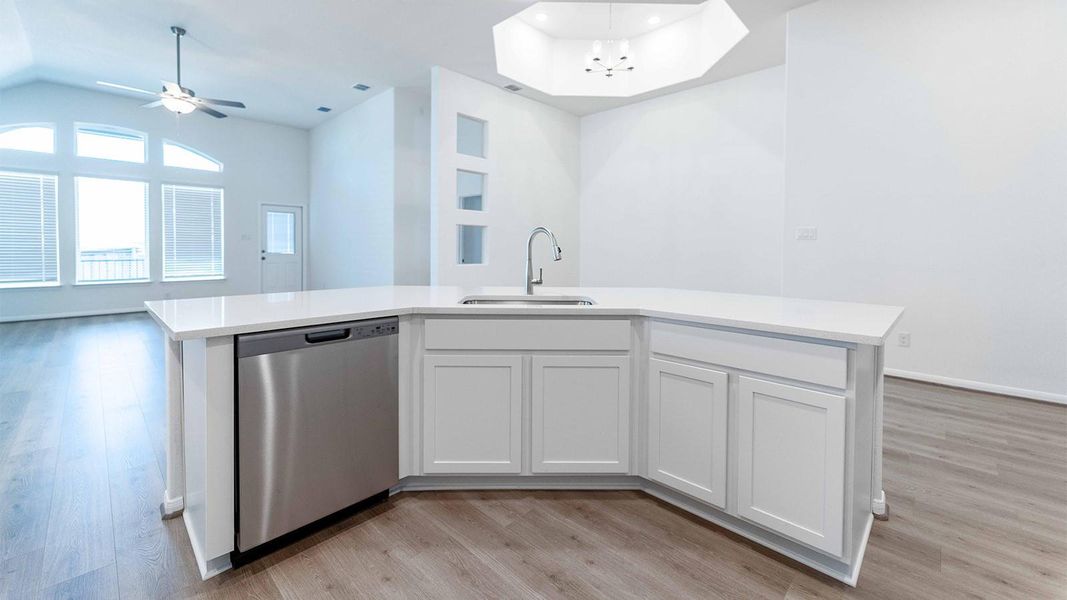 Kitchen with open floor plan, stainless steel dishwasher, a center island with sink, white cabinetry, and light wood-style floors