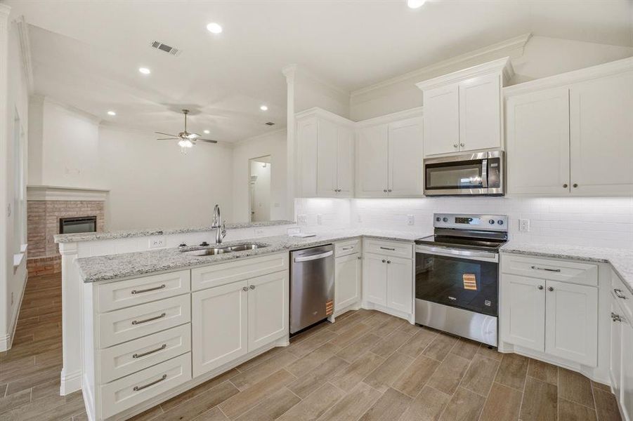 The kitchen features white cabinetry, granite countertops, and stainless steel appliances