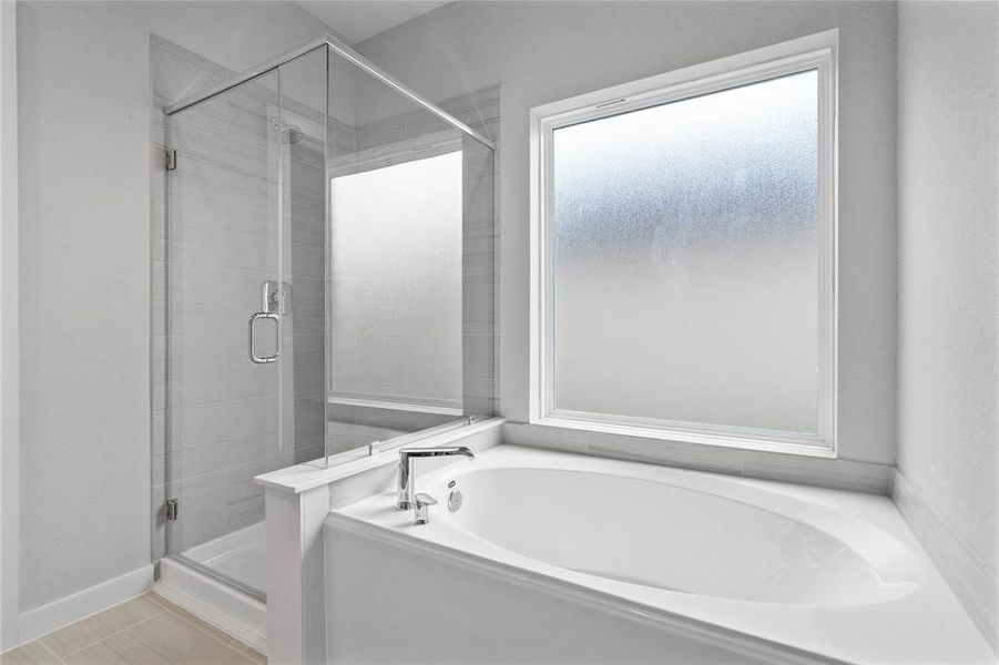 An additional view of this beautiful primary bathroom featuring a framed walk-in shower with tile surround, separate garden tub for soaking after a long day!