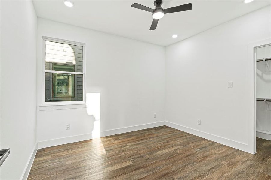Unfurnished bedroom with a spacious closet, dark wood finished floors, ceiling fan, and recessed lighting