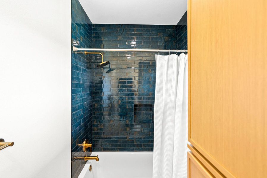 Richly textured tile lines the modern tub and shower alcove.
