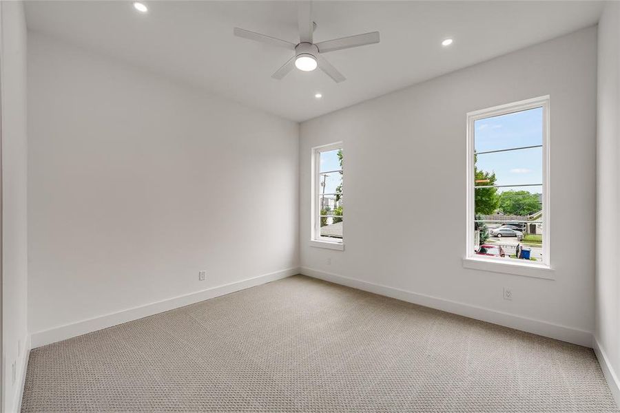 Bright room featuring two large windows, recessed lighting, a ceiling fan, and light-toned carpet flooring