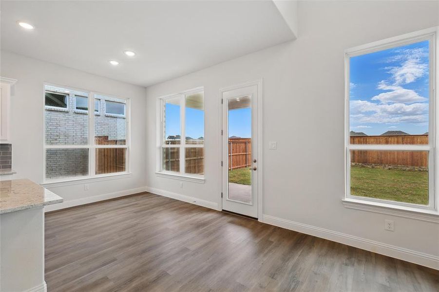 Unfurnished dining area featuring plenty of natural light, baseboards, wood finished floors, and recessed lighting