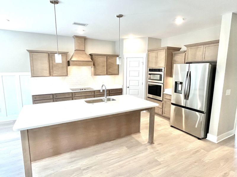 Kitchen with large quartz covered island and corner pantry