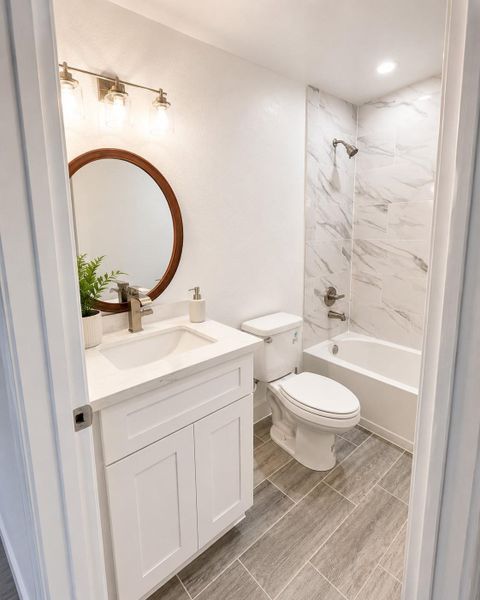 Elegant and modern bathroom featuring a modern vanity with a stylish mirror and a luxurious wall-tiled shower/bath combo.