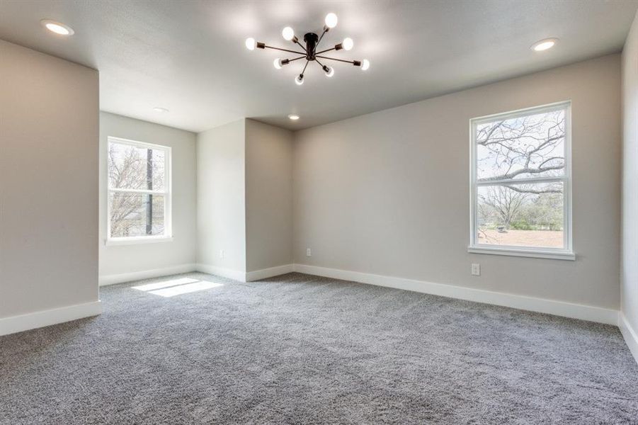 Carpeted spare room featuring an inviting chandelier