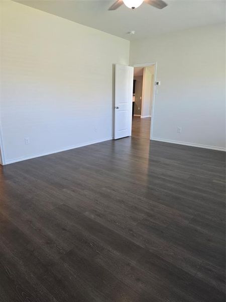 Empty room with ceiling fan and dark wood-type flooring