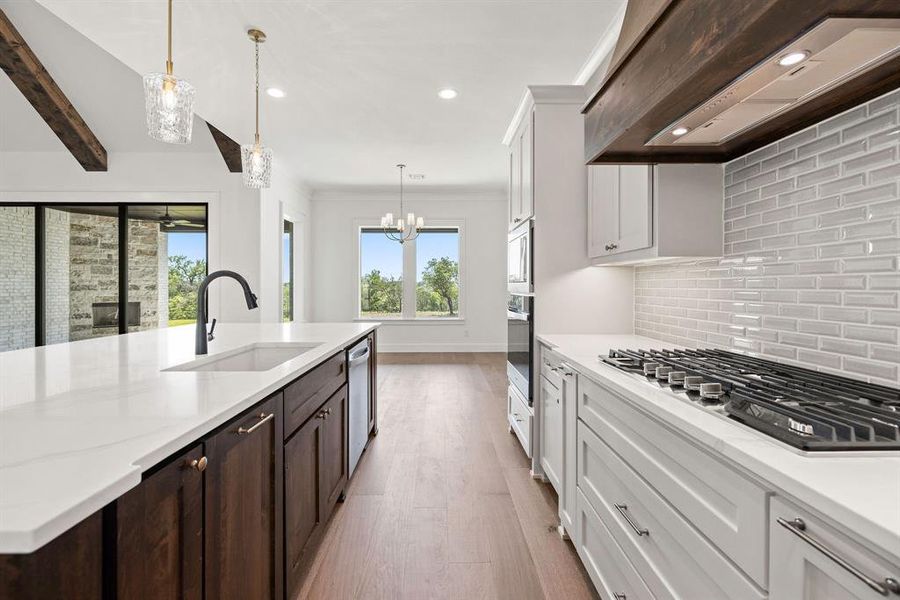 Kitchen with a wealth of natural light, wall chimney exhaust hood, stainless steel appliances, and a sink