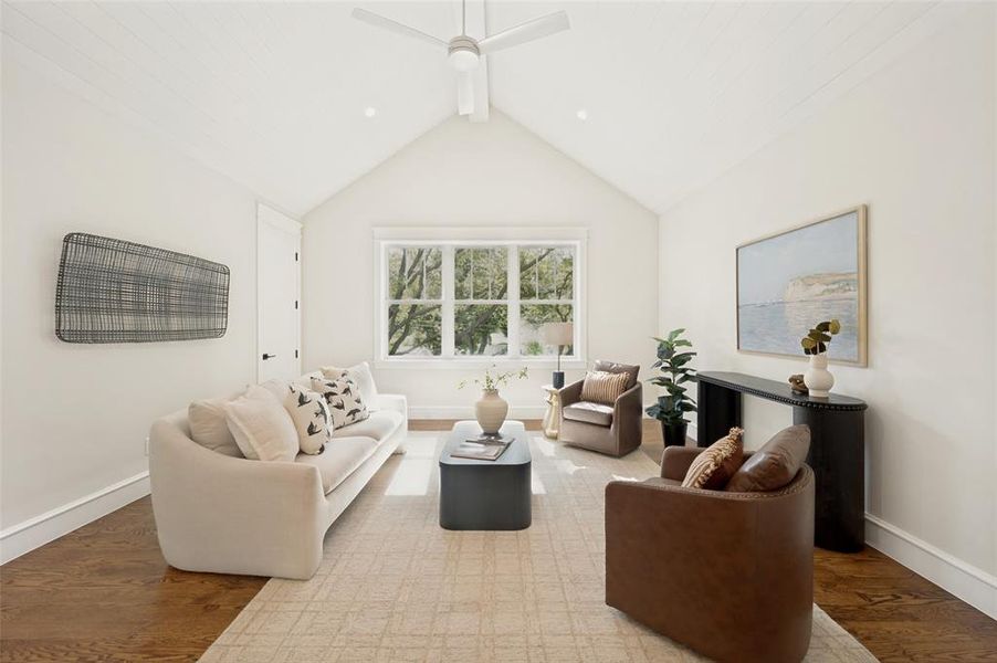 Vaulted ceiling with a contemporary ceiling fan, large window, wood-finish flooring, and white trim throughout