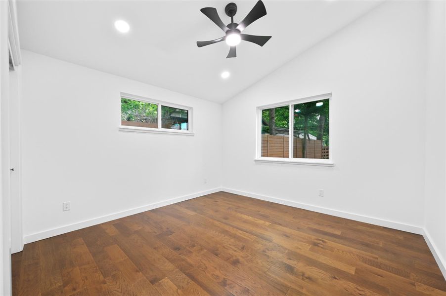 Empty room with lofted ceiling, baseboards, recessed lighting, dark wood-style floors, and ceiling fan