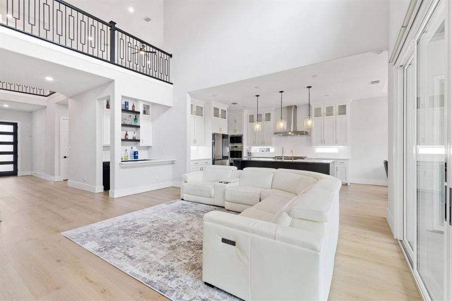Living room with light wood finished floors, a high ceiling, and recessed lighting