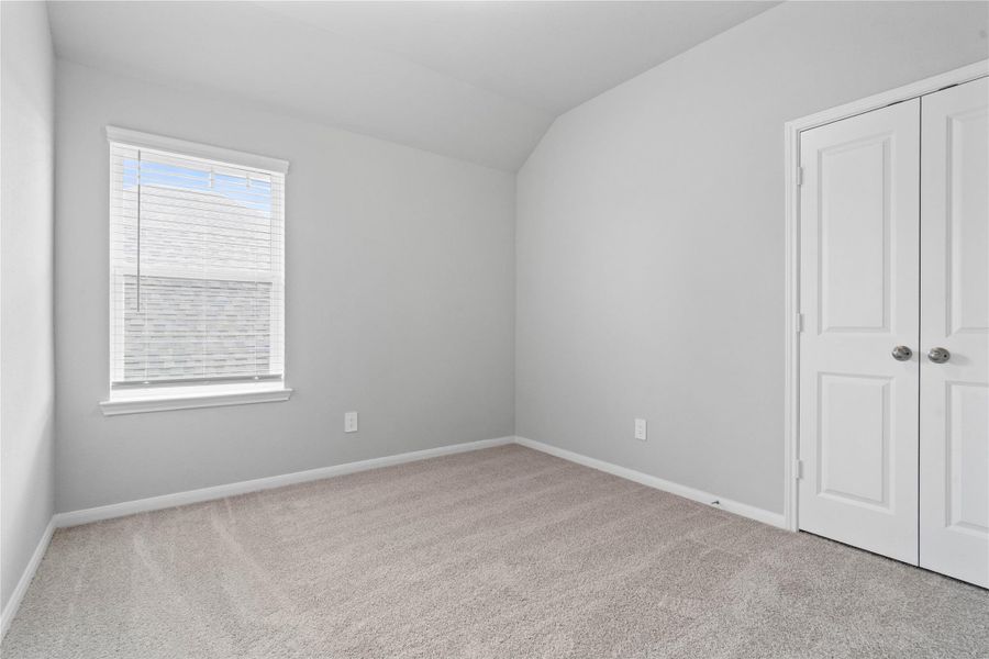 Perfect for guests or a quiet home office, this room features soft plush carpeting, a window with fitted blinds, sloped ceiling, and ample sized closet space.
