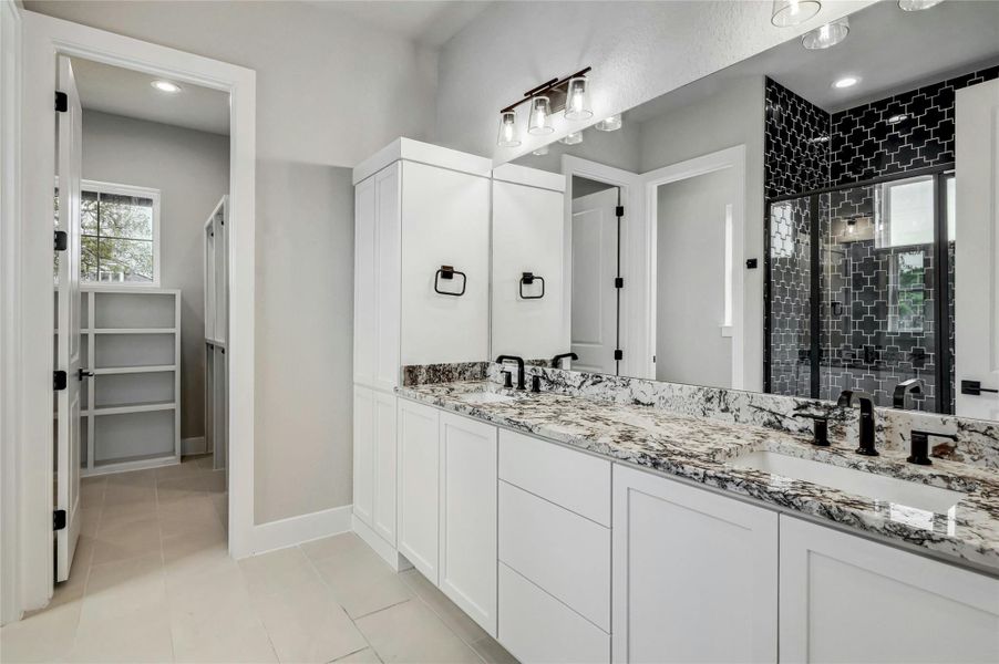 Full bath with a stall shower, tile patterned flooring, a sink, and baseboards