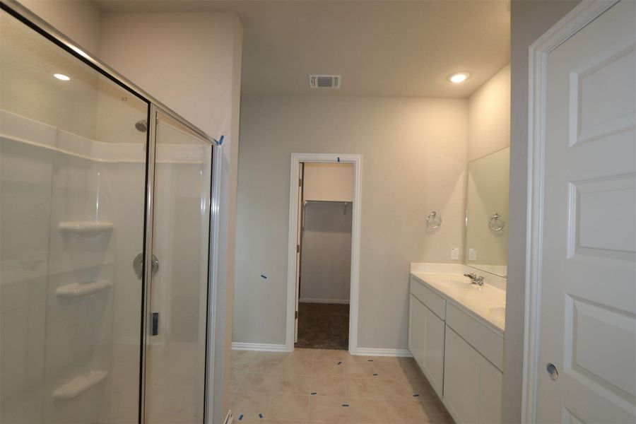 Bathroom featuring a shower with door, tile patterned floors, and vanity