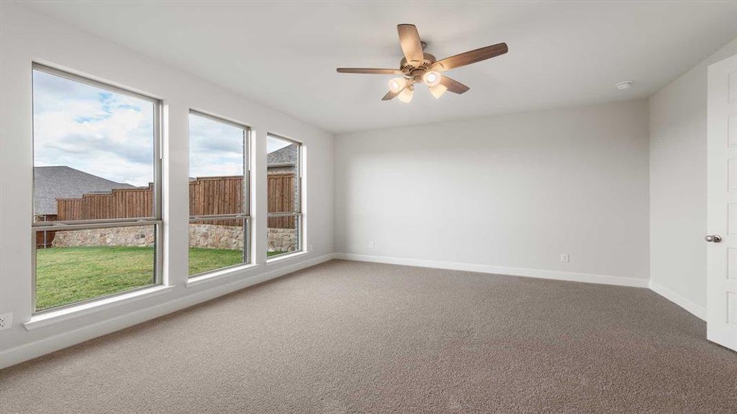 Carpeted spare room featuring ceiling fan