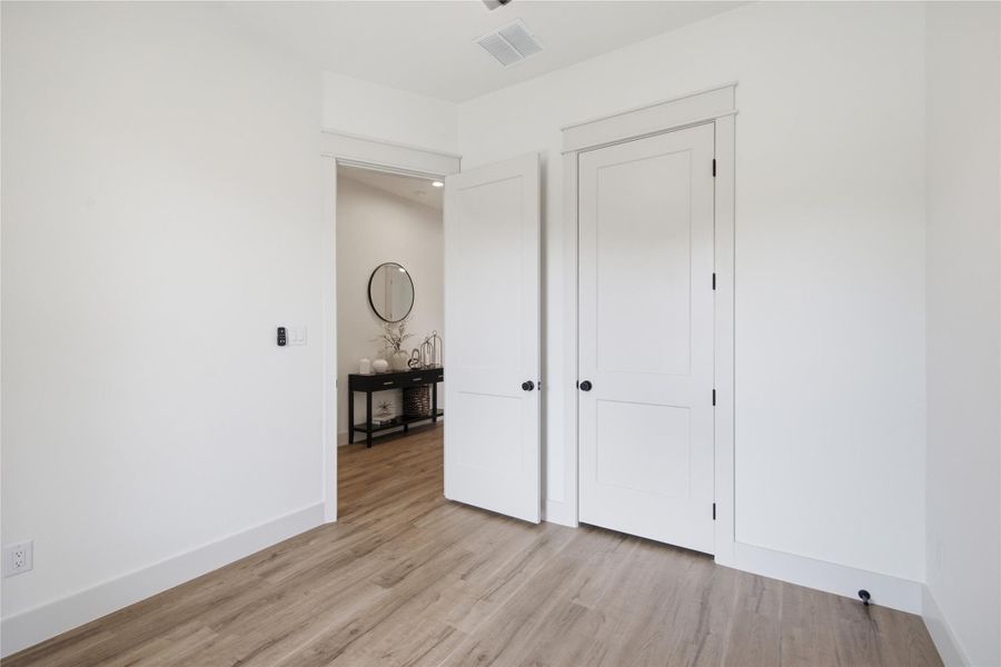 Well-lit room with wood-look flooring and crisp white doors offers versatile living space. Well-lit room with wood-look flooring and crisp white doors offers versatile living space.