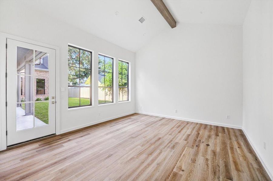 The secluded guest suite features a vaulted ceiling with a wooden beam accent, adding character to the space. Large windows bring in plenty of natural light, offering views of the backyard. Guest suite has en suite full bathroom and walk in closet.